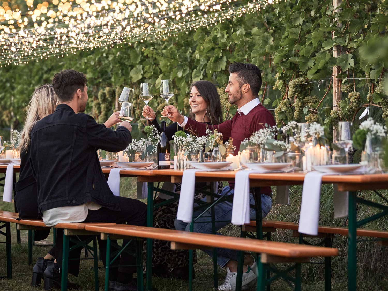 Quattro persone brindano con un vino su un set da birreria classico nella natura.